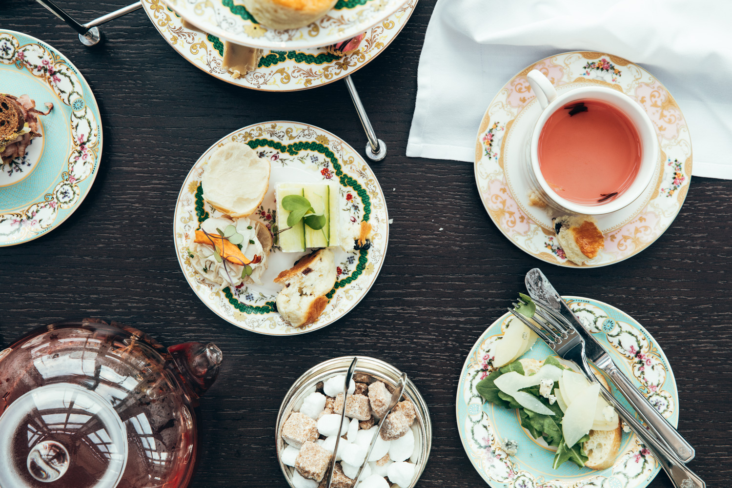 Table flat lay of tea in teacups and small bites on saucers