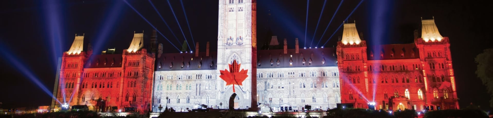 parliament building lit up with the canadian flag